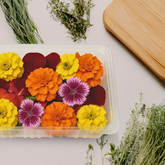 Assorted edible flowers in a clear container, ideal for upscale cocktails, gourmet dishes, and food styling.